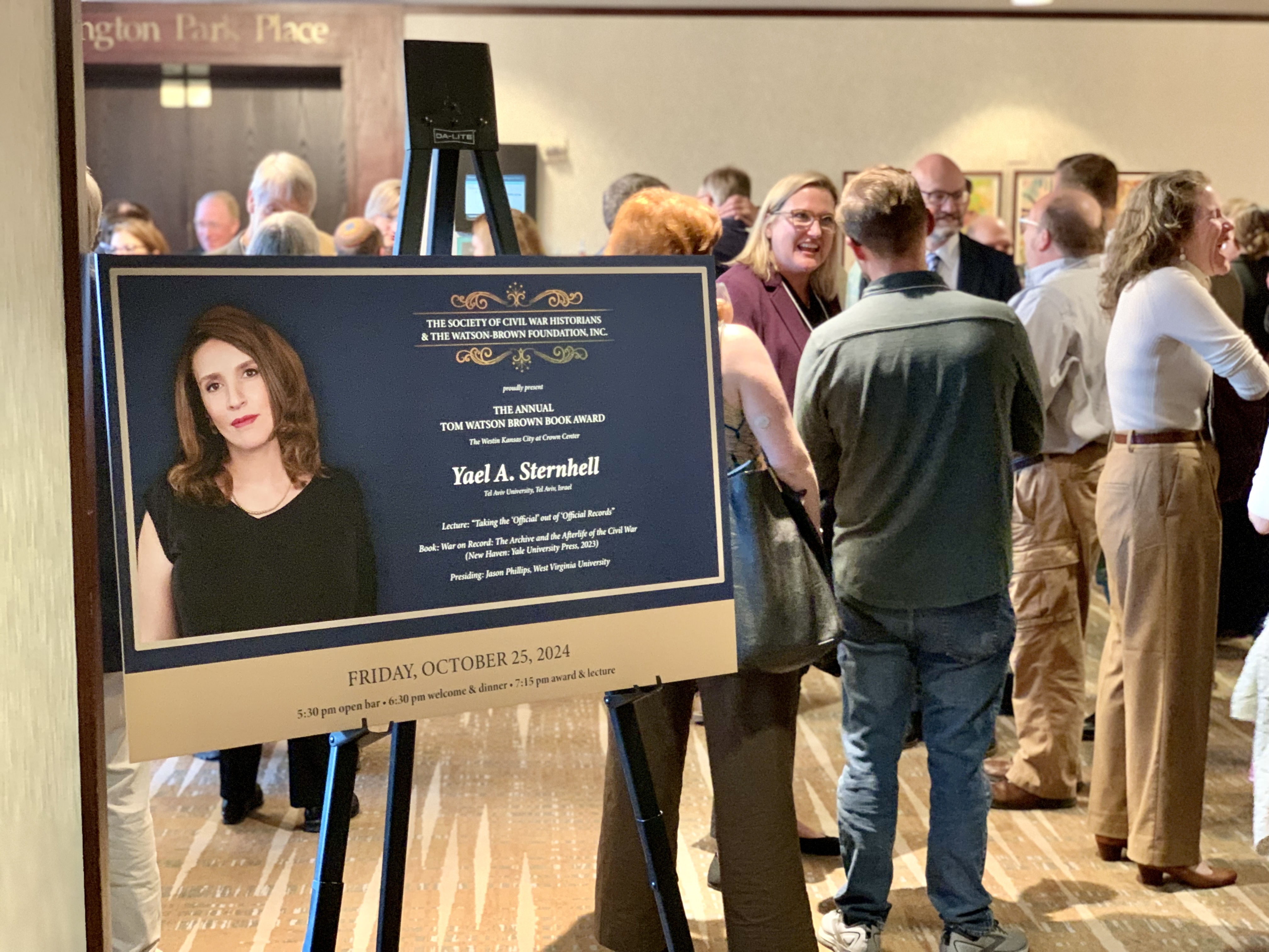 Poster advertising the event in front of attendees during a happy hour